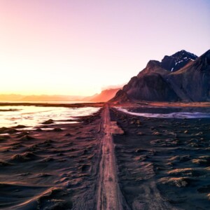 Road leads through landscape at sunset.